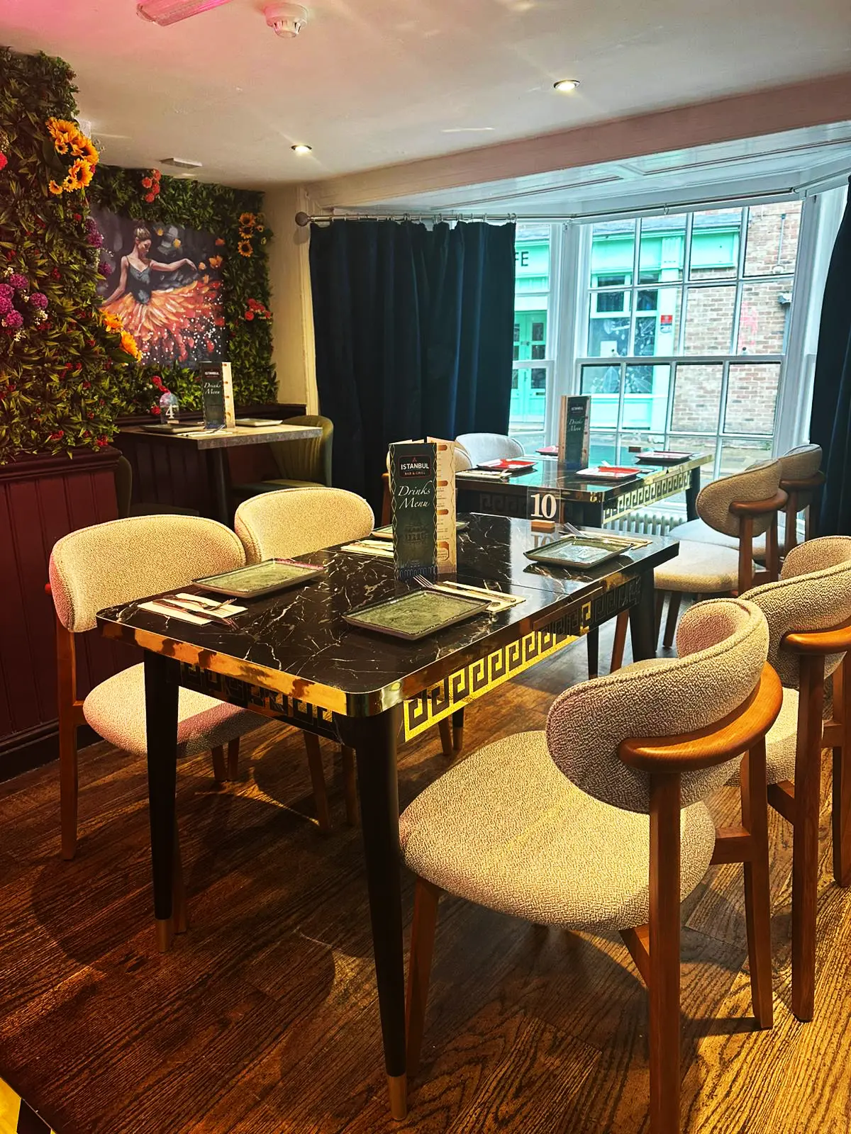 Curved dining chairs around a table beside the window